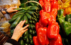 A greengrocer arranges zucchinis and sweet peppers on a vegetables stall in Marseille